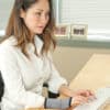 woman using IMAK arthritis wrist sleeve while at computer in a white blouse
